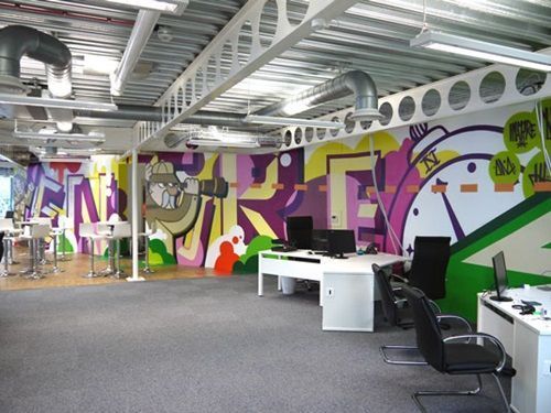 Decoração industrial com grafite e desenhos coloridos nas paredes.
