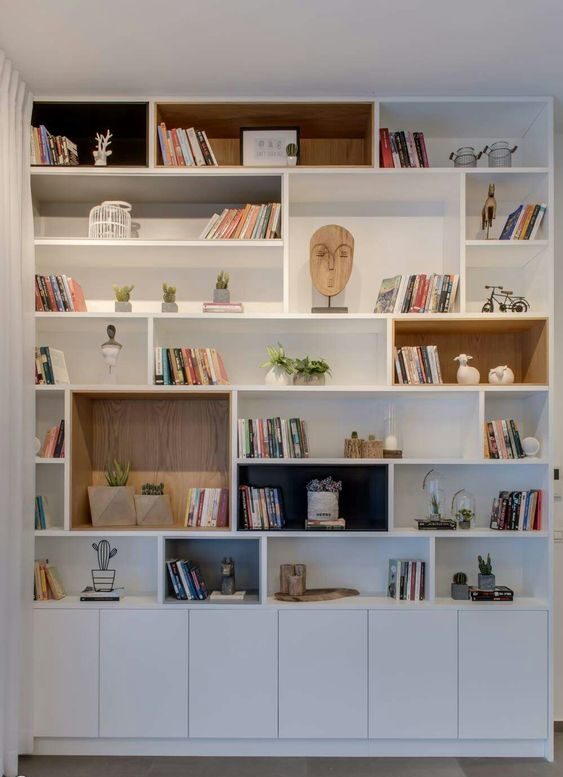 Como uma estante pode ser organizada para termos uma biblioteca e ao mesmo tempo incluir elementos decorativos, gerando ligação e harmonia entre os itens.